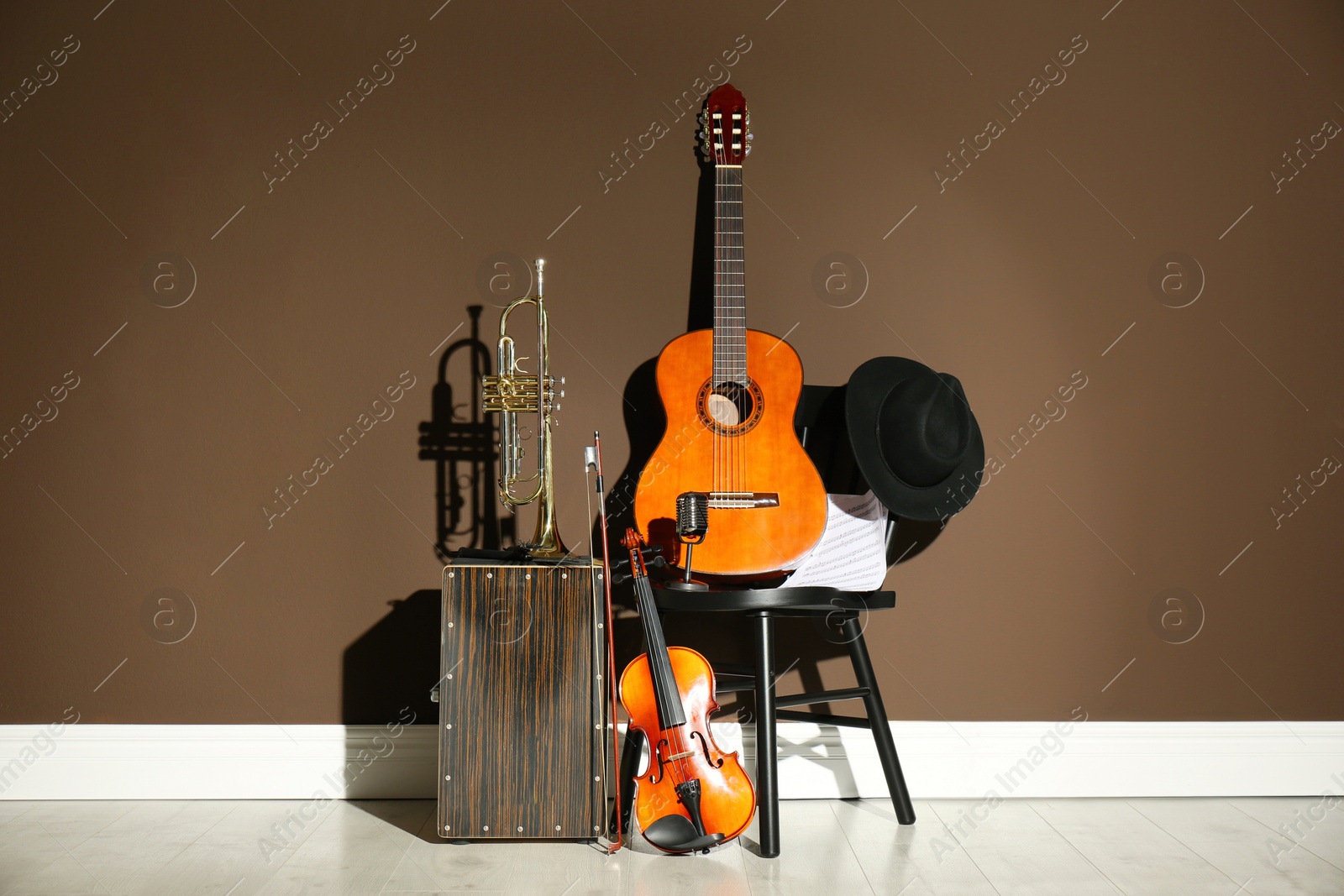 Photo of Set of different musical instruments near brown wall indoors