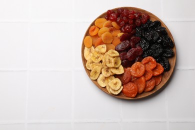 Photo of Delicious dried fruits on white tiled table, top view. Space for text