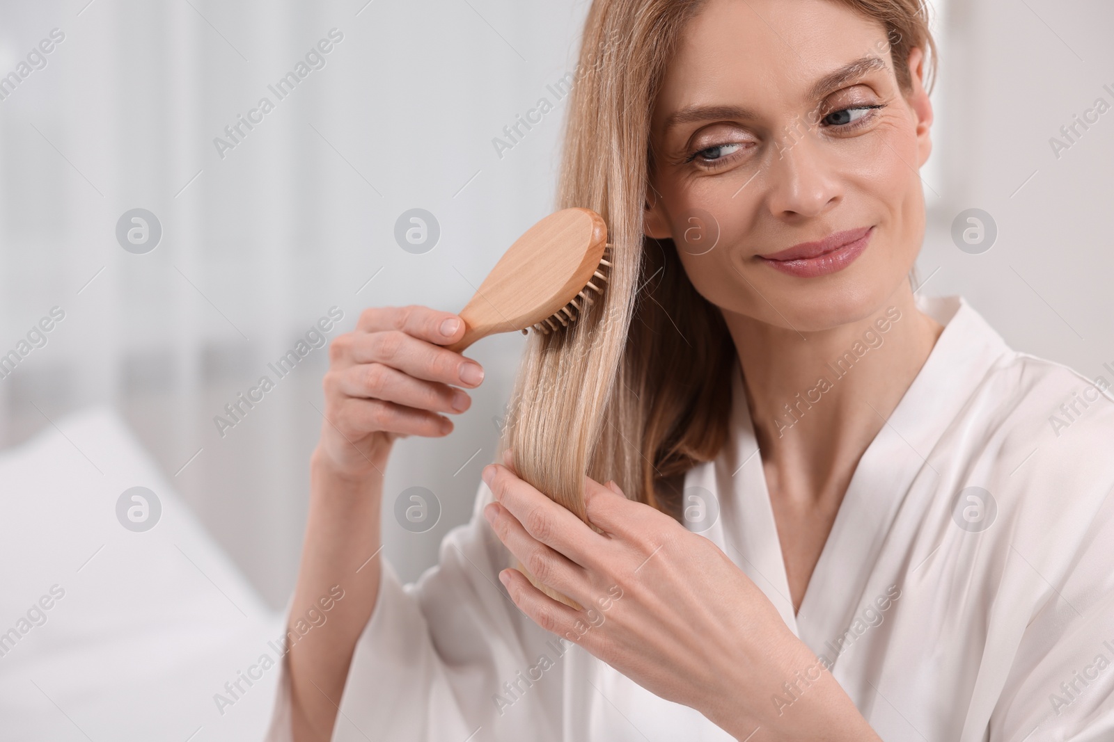 Photo of Beautiful woman brushing her hair in room