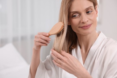 Beautiful woman brushing her hair in room