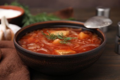 Photo of Bowl of delicious borscht on wooden table, closeup