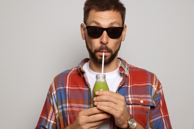 Man drinking delicious juice on grey background