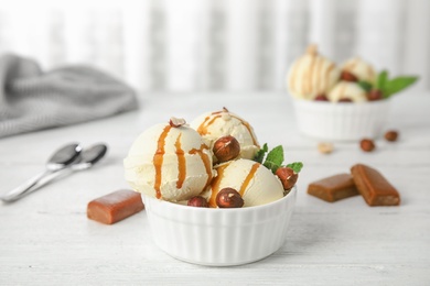 Photo of Delicious ice cream served with caramel and hazelnuts served on table