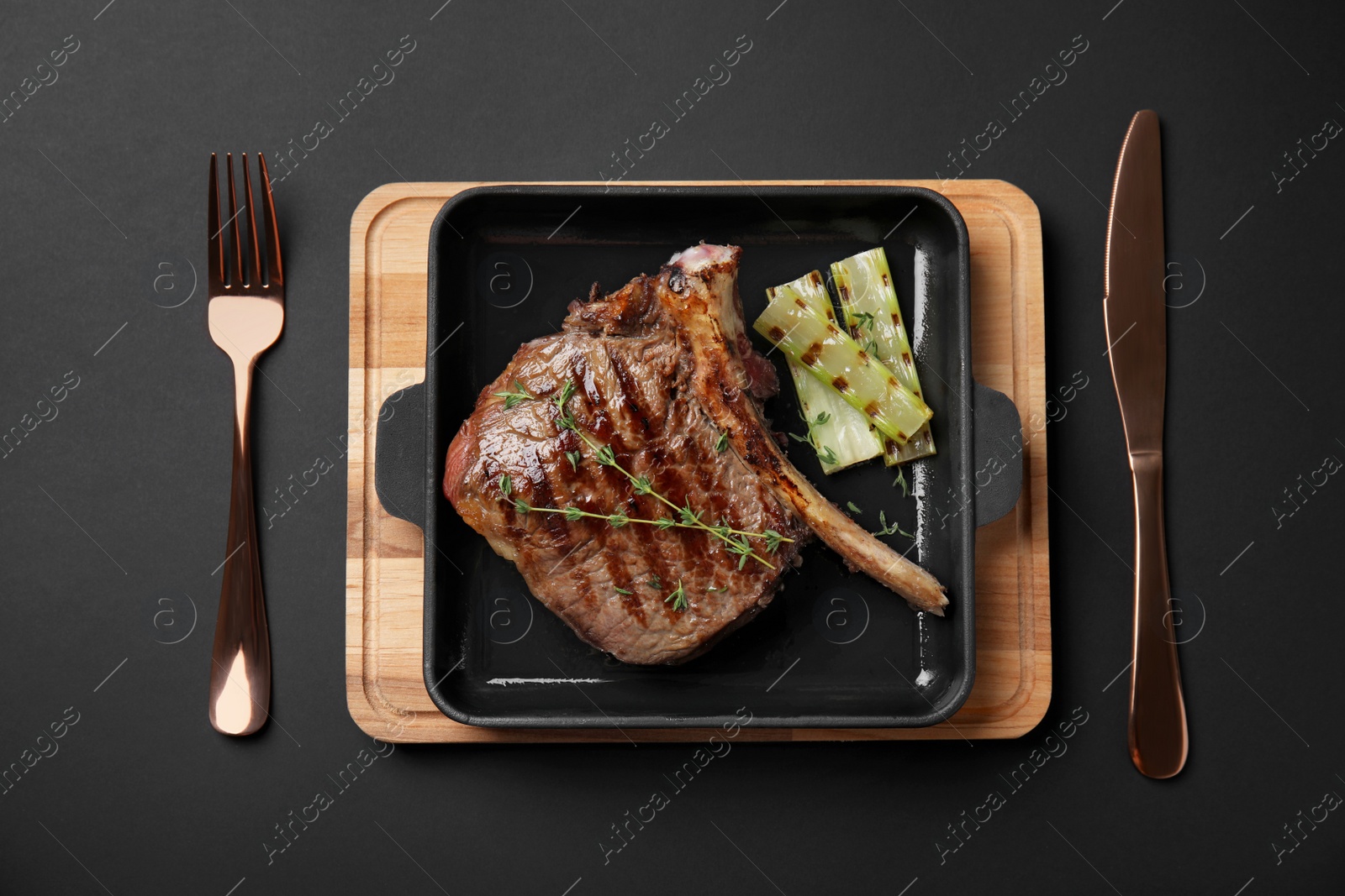 Photo of Grill pan with barbecued meat on black background, top view