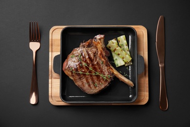 Photo of Grill pan with barbecued meat on black background, top view