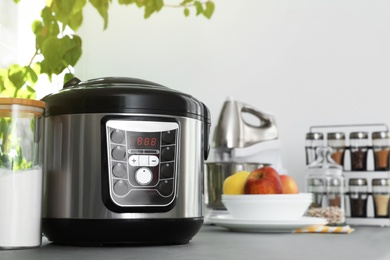 Photo of New modern multi cooker and jar of flour on table in kitchen. Space for text