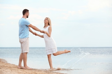Happy romantic couple dancing on beach, space for text