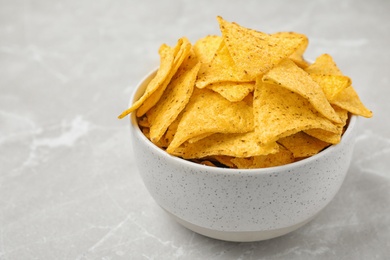 Photo of Bowl with tasty Mexican nachos chips on grey table, space for text