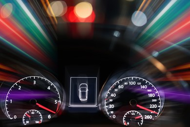 Image of Speedometer and tachometer behind steering wheel in car, motion blur effect