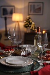 Christmas table setting with bottle of wine, appetizers and dishware indoors