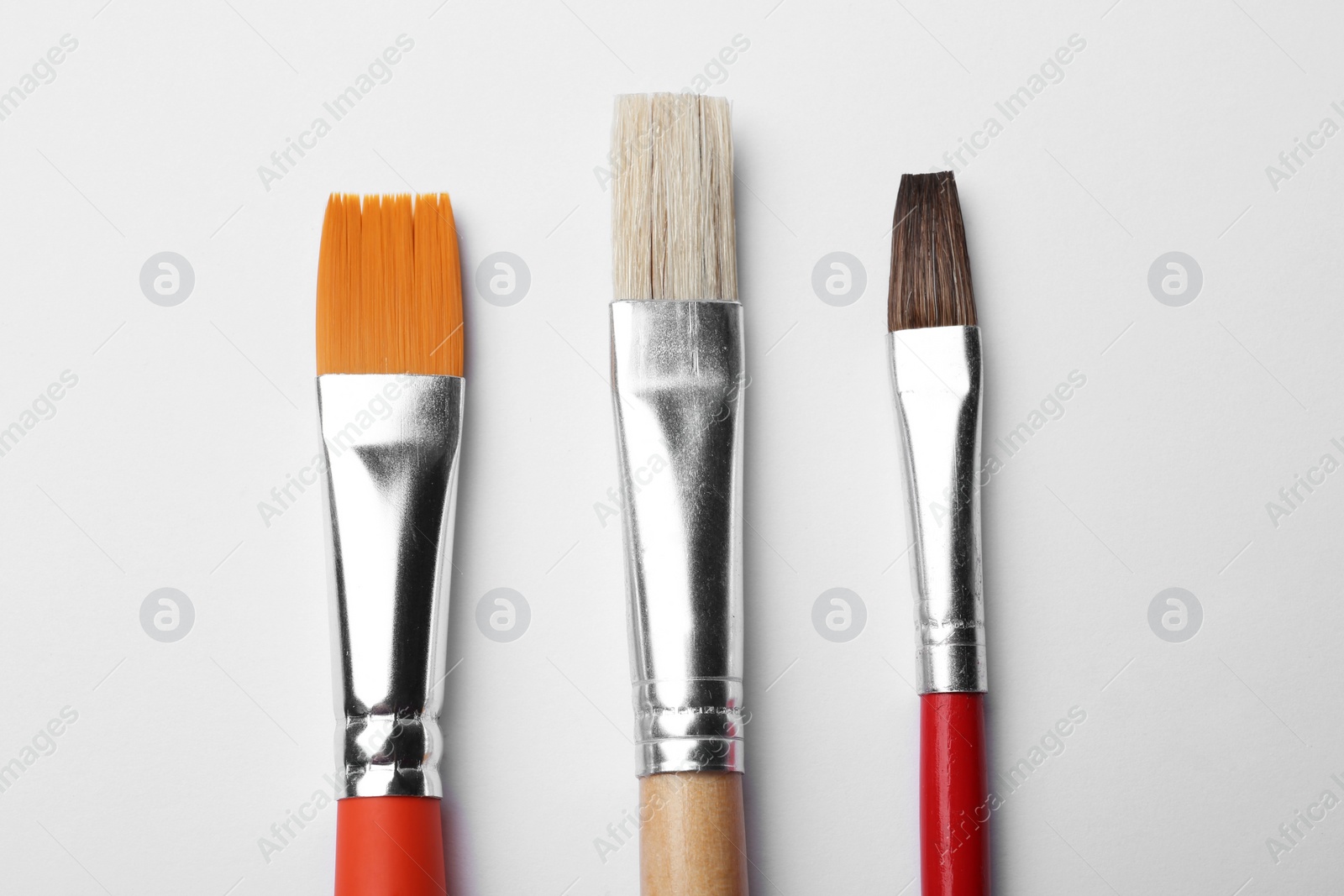 Photo of Different paint brushes on white background, top view