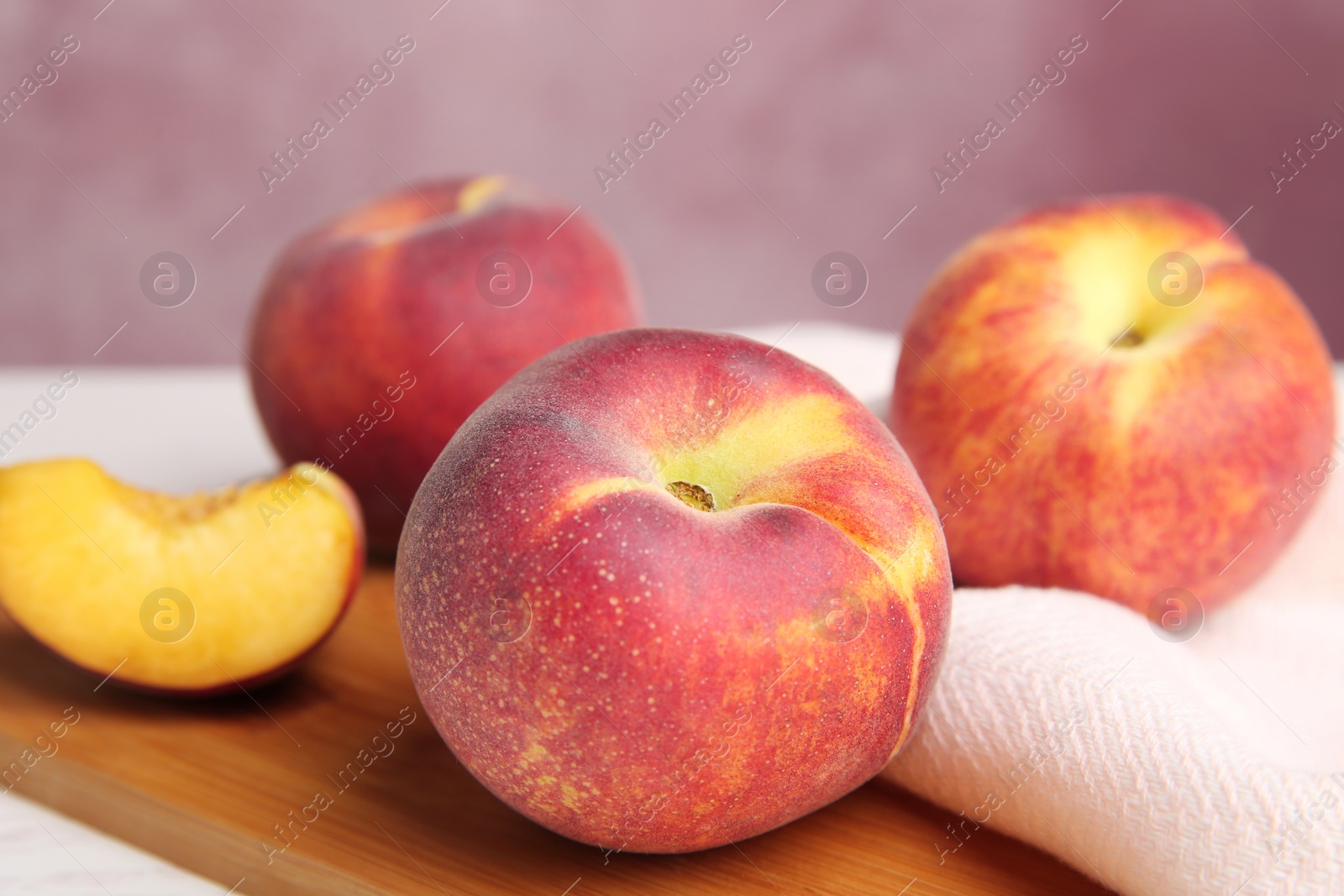 Photo of Board with fresh peaches and fabric on table