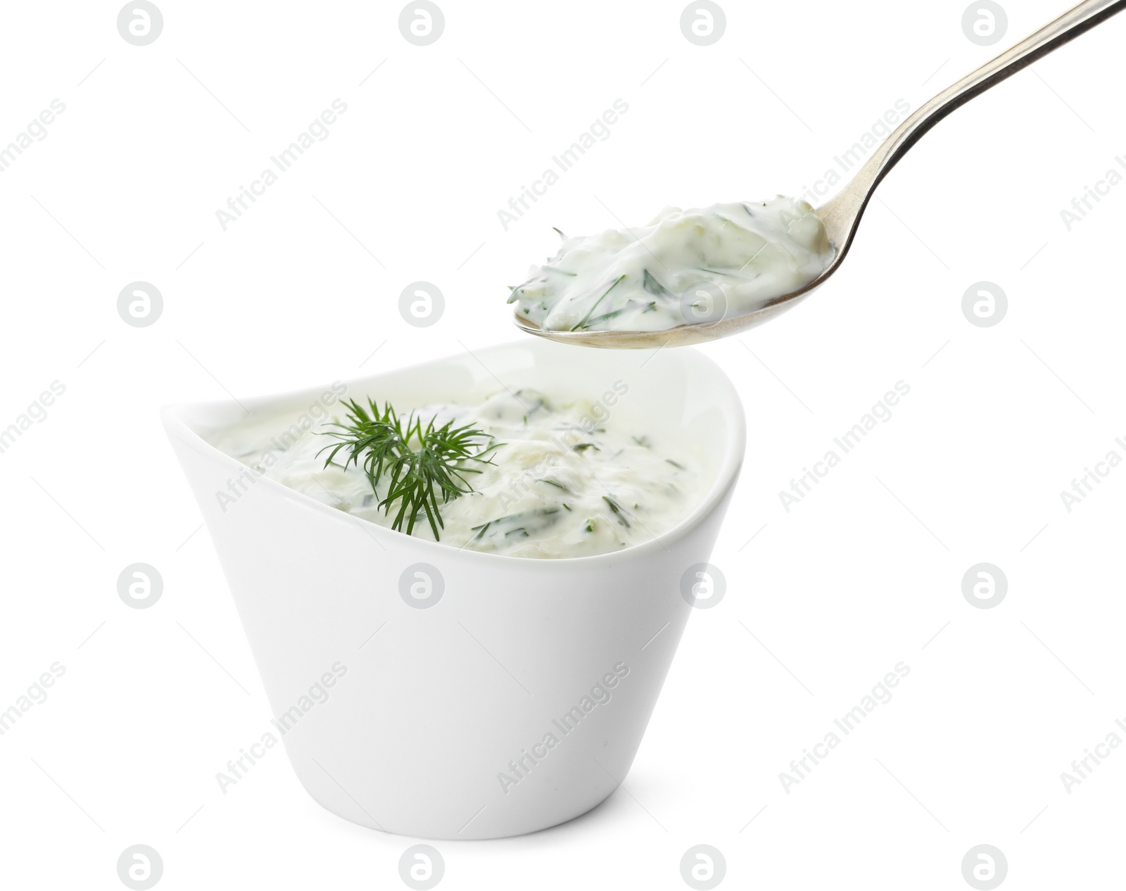 Photo of Spoon and bowl of cucumber sauce on white background. Traditional Tzatziki