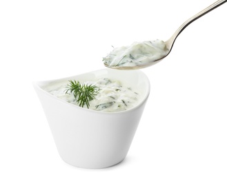 Photo of Spoon and bowl of cucumber sauce on white background. Traditional Tzatziki