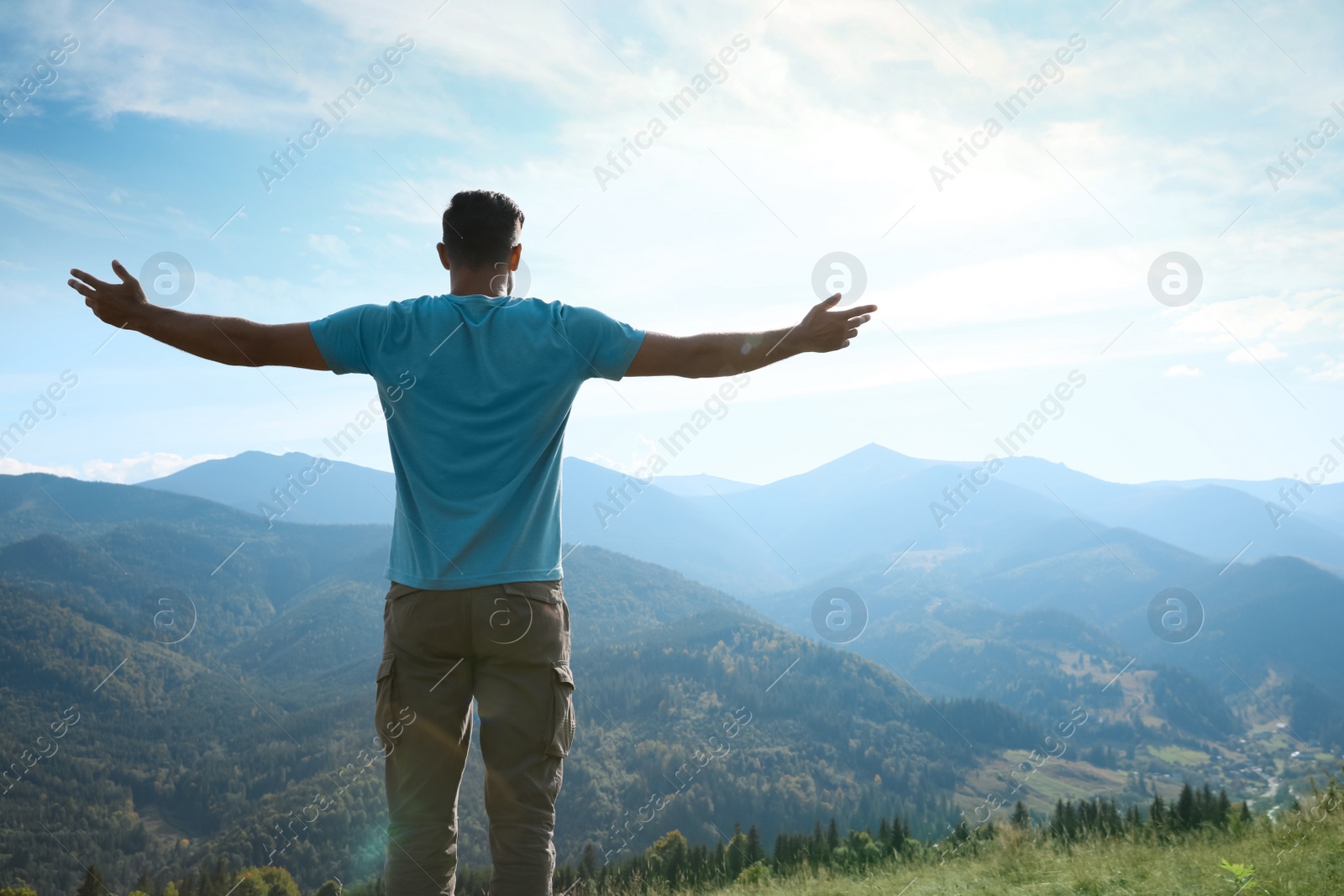 Photo of Tourist in mountains on sunny day, back view