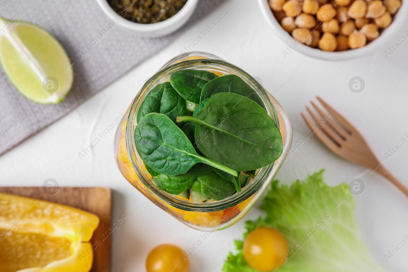 Photo of Healthy salad in glass jar on light table, flat lay