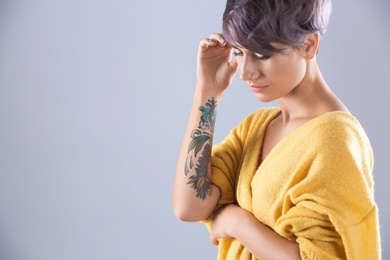 Young woman with tattoo on color background. Space for text