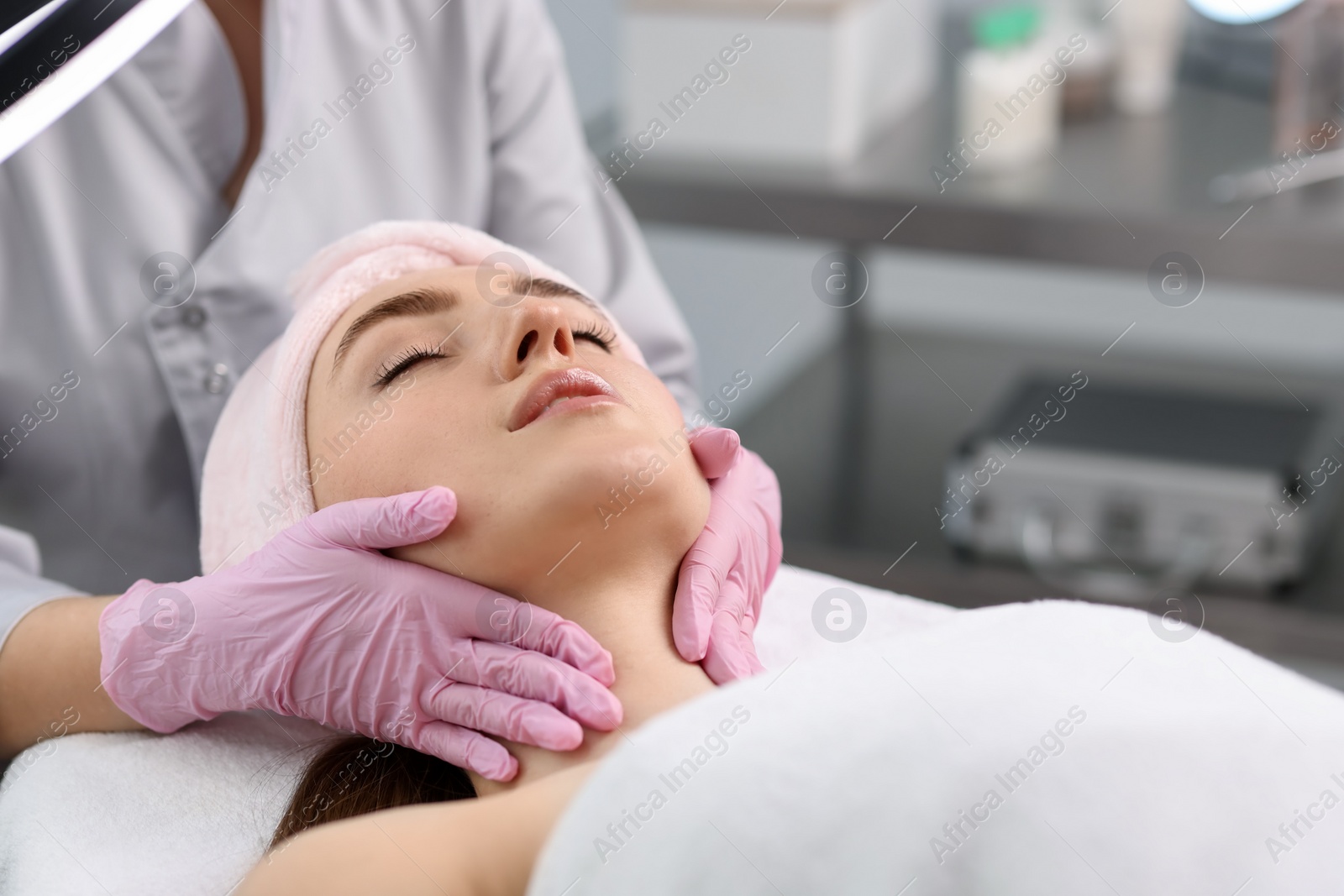 Photo of Cosmetologist making face massage to client in clinic, closeup. Space for text