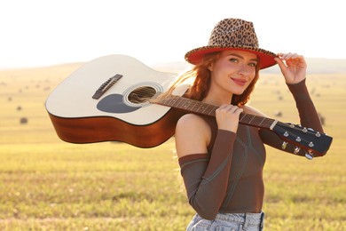 Beautiful happy hippie woman with guitar in field
