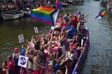 Photo of AMSTERDAM, NETHERLANDS - AUGUST 06, 2022: Many people in boats at LGBT pride parade on river