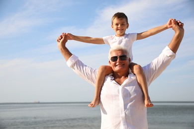 Photo of Cute little boy with grandfather spending time together near sea