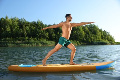 Photo of Man practicing yoga on color SUP board on river