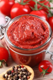 Jar of tasty tomato paste and ingredients on table, closeup