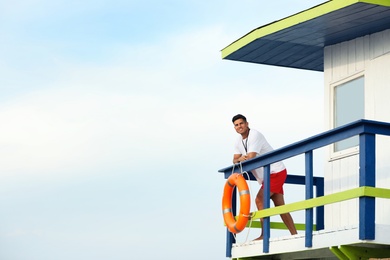 Male lifeguard on watch tower against blue sky