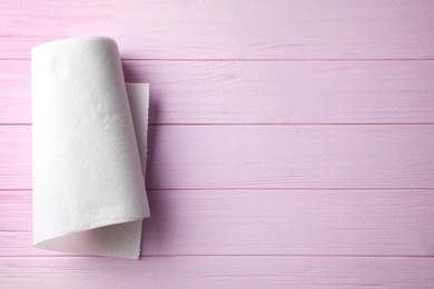 Photo of Roll of paper towel on pink wooden table, top view. Space for text