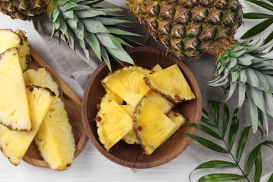 Photo of Pieces of tasty ripe pineapple on white wooden table, flat lay