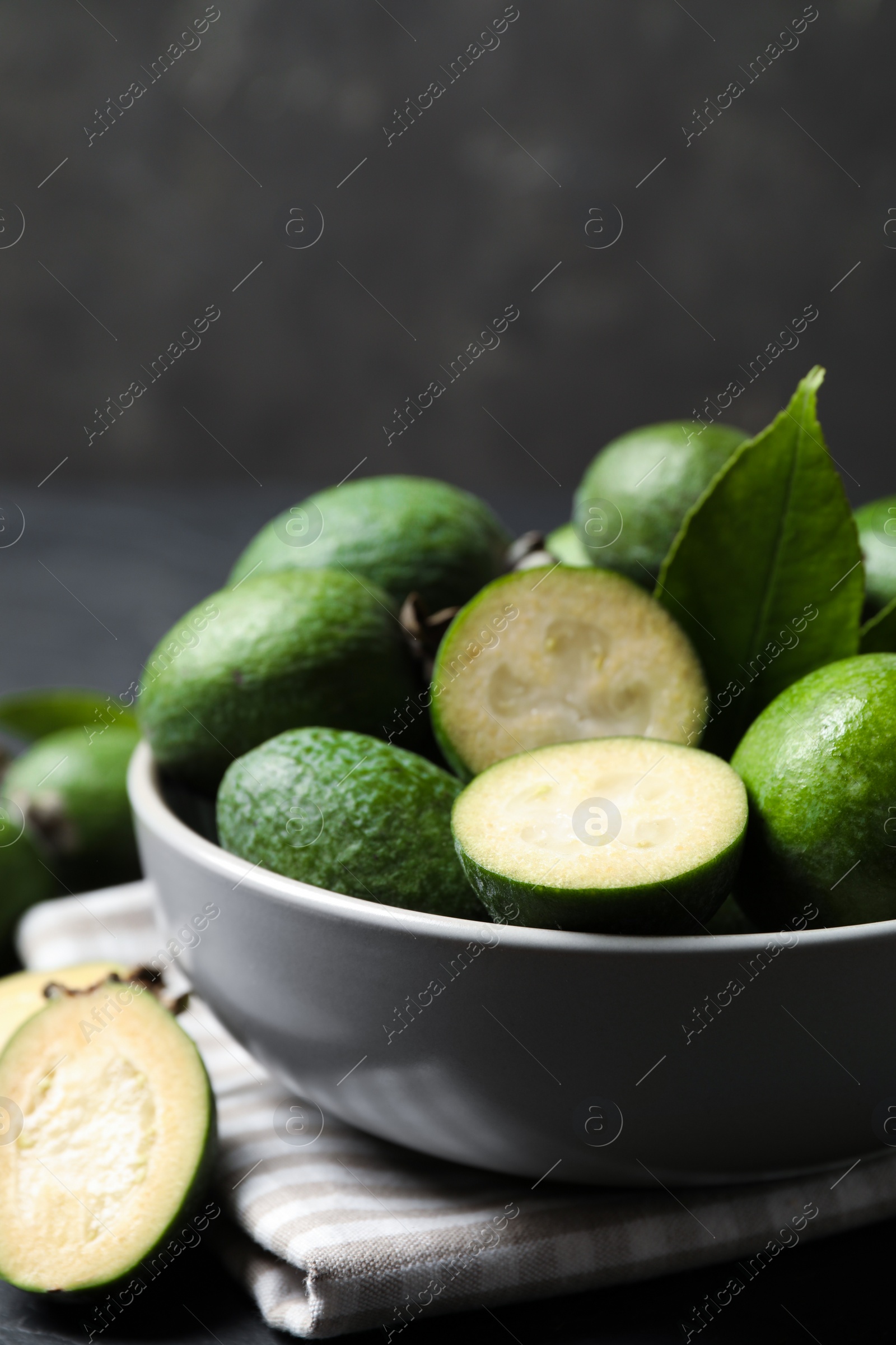 Photo of Fresh green feijoa fruits in bowl, closeup. Space for text