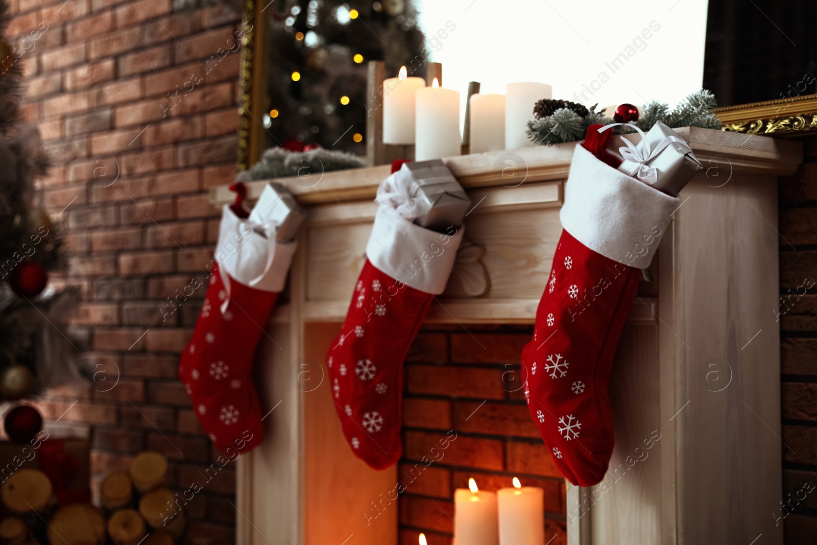 Photo of Decorative fireplace with Christmas stocking and gifts in stylish room interior