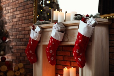 Decorative fireplace with Christmas stocking and gifts in stylish room interior