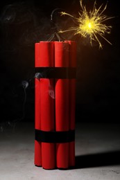 Image of Dynamite bomb with lit fuse on grey table
