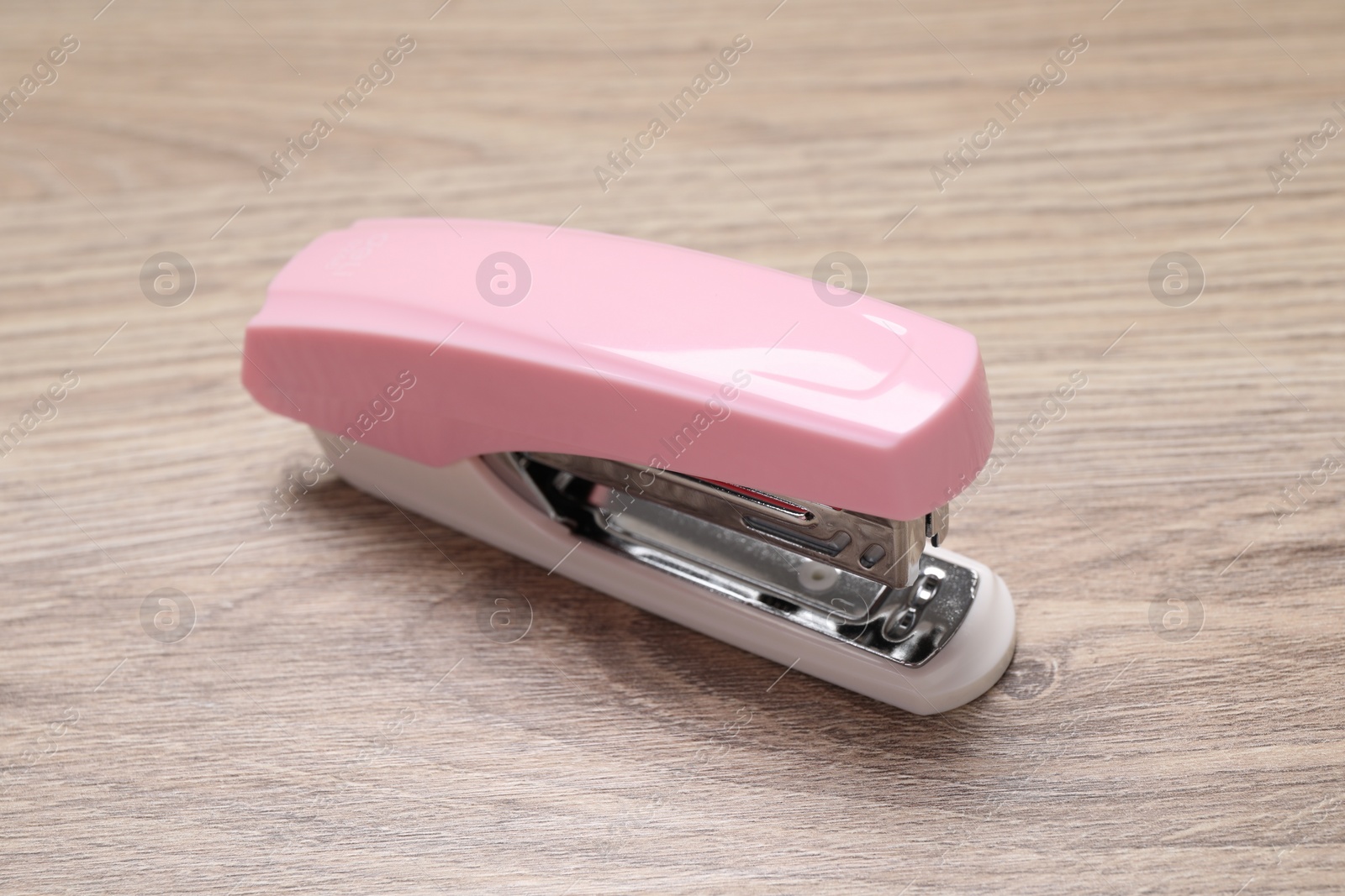 Photo of One new pink stapler on wooden table