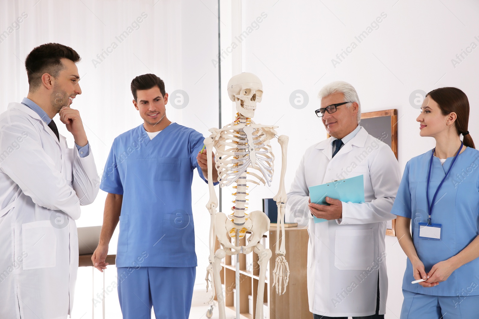 Photo of Medical students and professor studying human skeleton anatomy in classroom