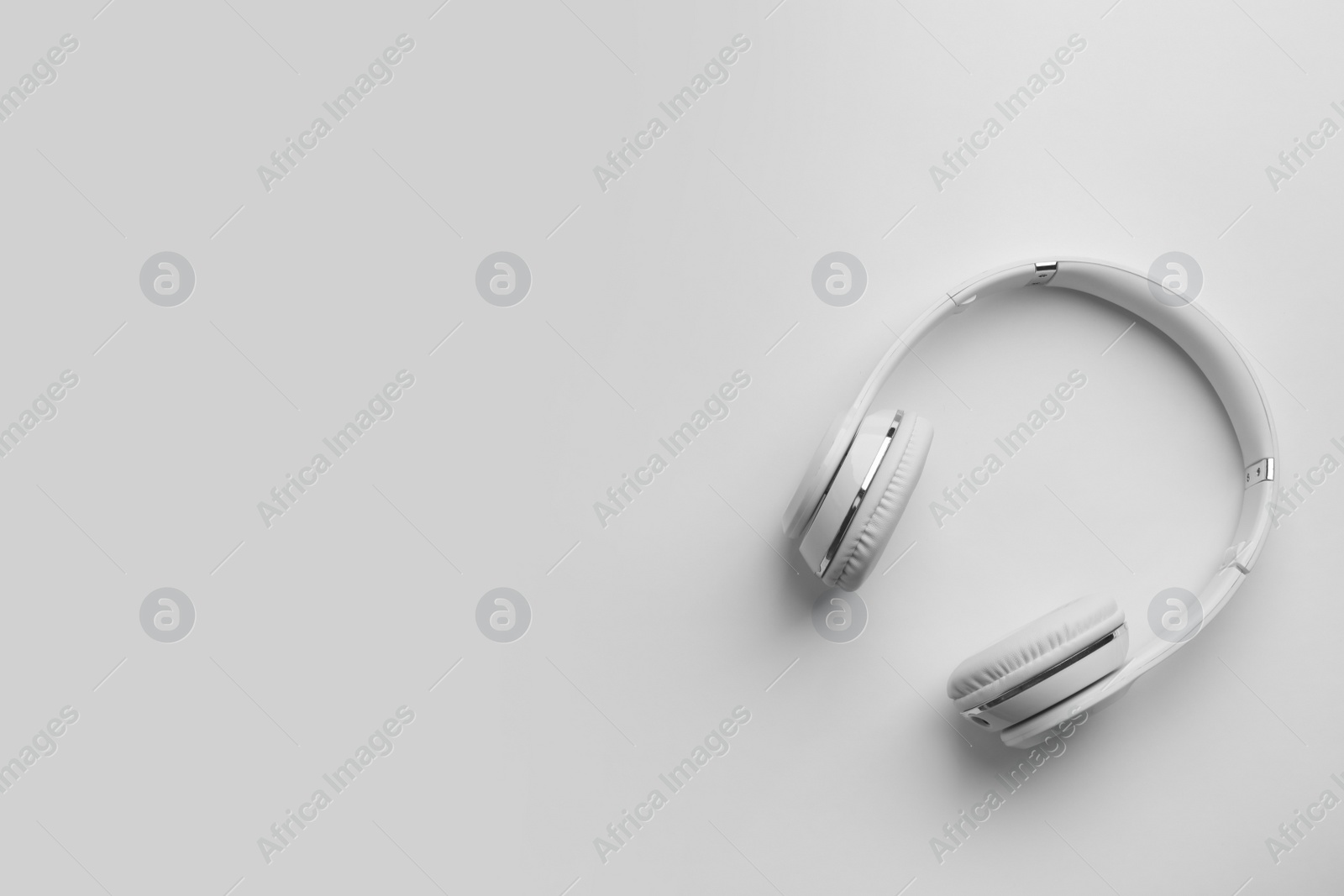 Photo of Stylish modern headphones with earmuffs on white background, top view. Space for text