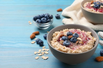 Photo of Tasty oatmeal porridge with toppings on light blue wooden table. Space for text