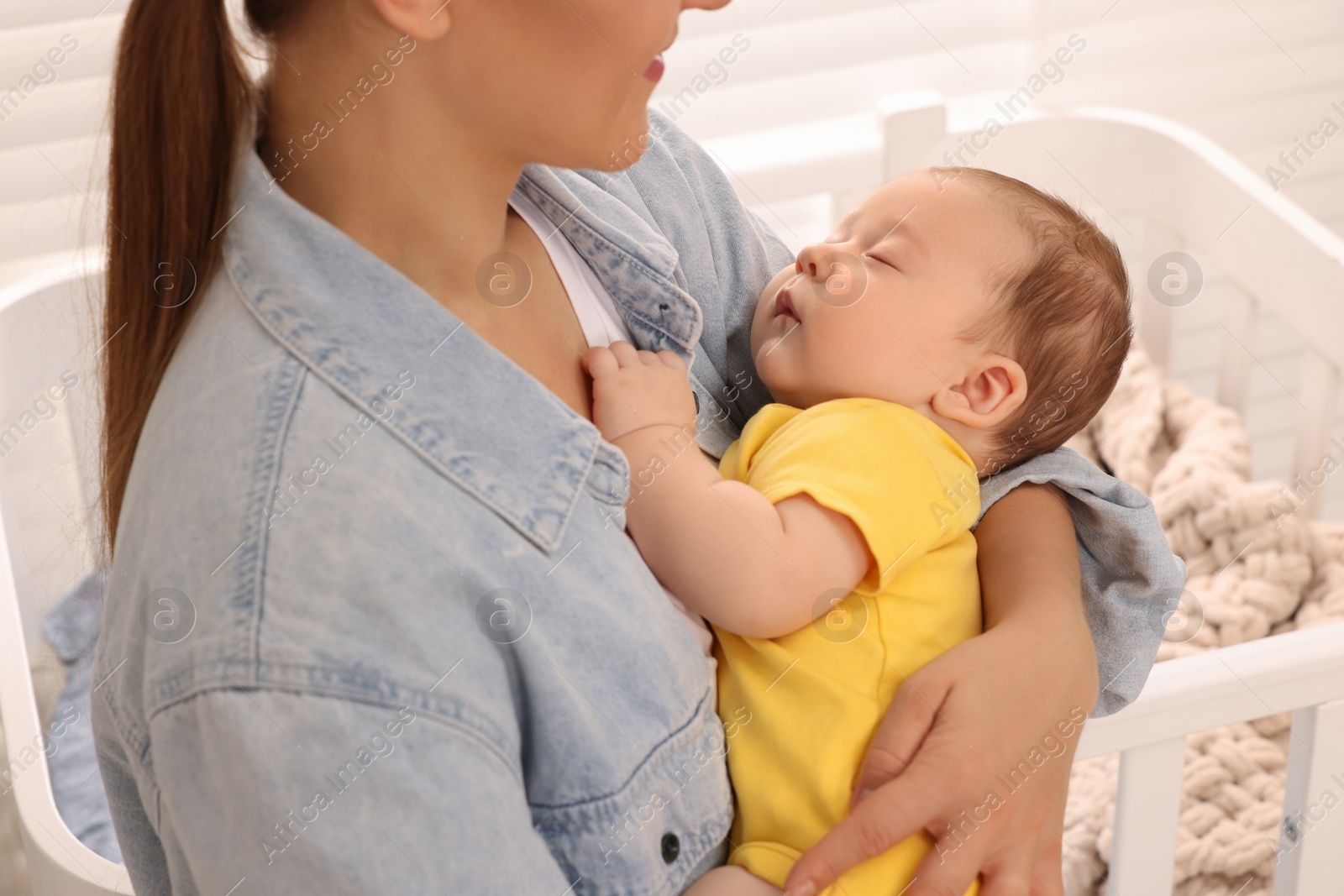 Photo of Mother holding her sleeping newborn baby at home, closeup