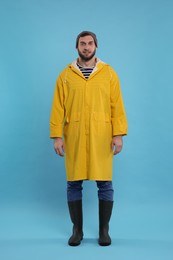 Photo of Fisherman in yellow raincoat on light blue background