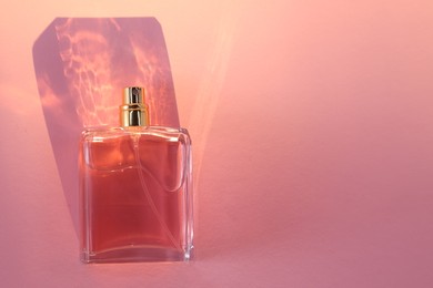 Photo of Luxury women's perfume in bottle on pink background. Space for text