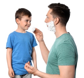 Photo of Dad applying shaving foam onto son's face against white background