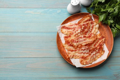 Delicious fried bacon slices on blue wooden table, top view. Space for text