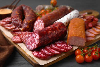 Different types of delicious sausages on black wooden table, closeup