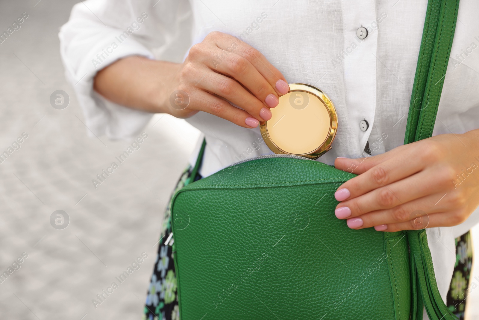 Photo of Woman taking cosmetic pocket mirror from bag outdoors, closeup