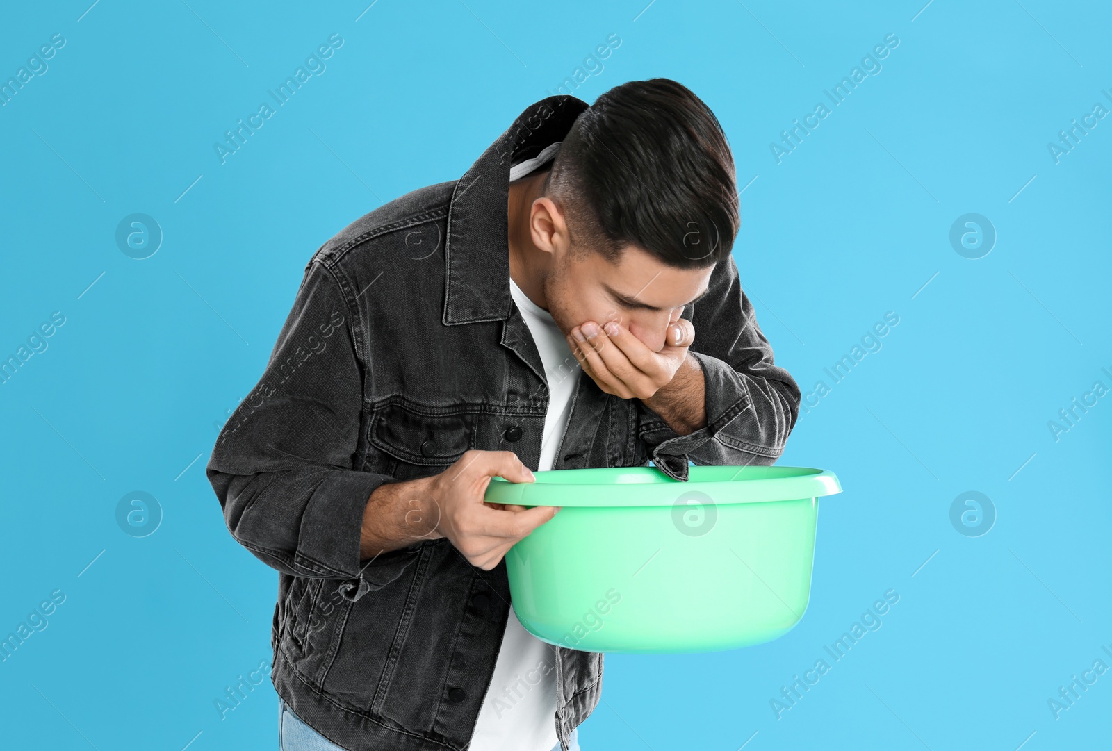 Photo of Man with basin suffering from nausea on light blue background. Food poisoning