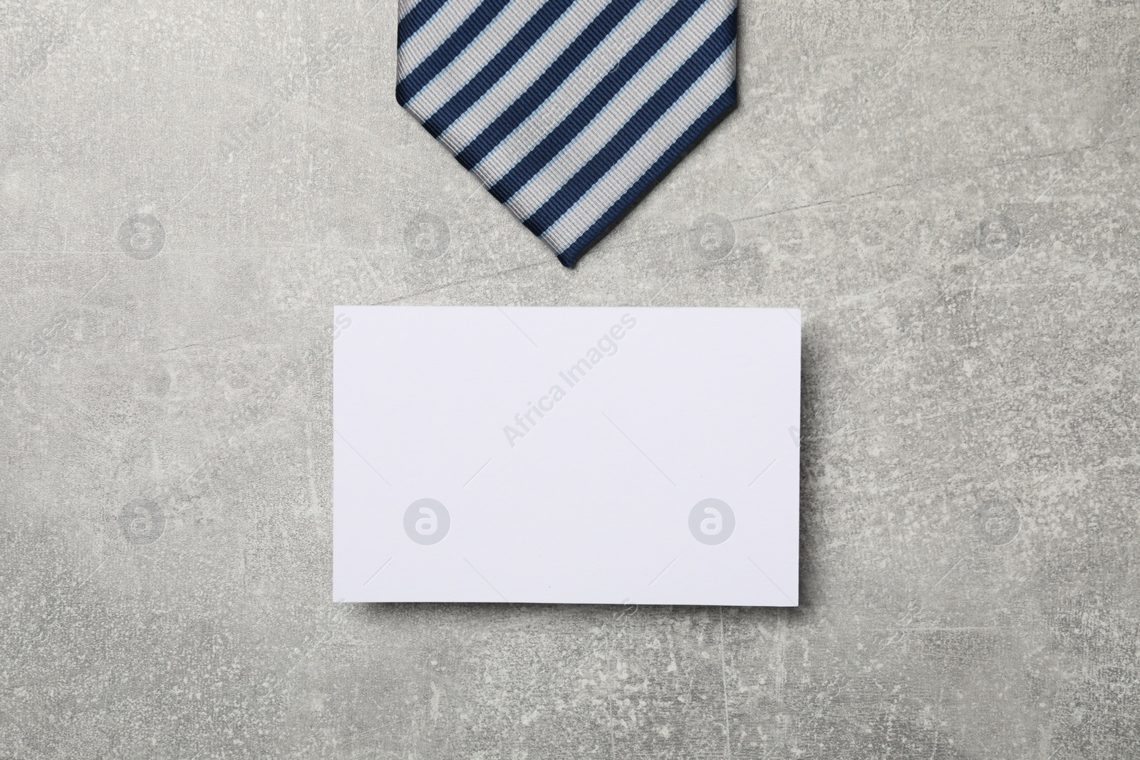 Photo of Striped tie and blank card on light grey table, flat lay. Business lunch concept