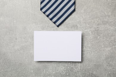 Photo of Striped tie and blank card on light grey table, flat lay. Business lunch concept
