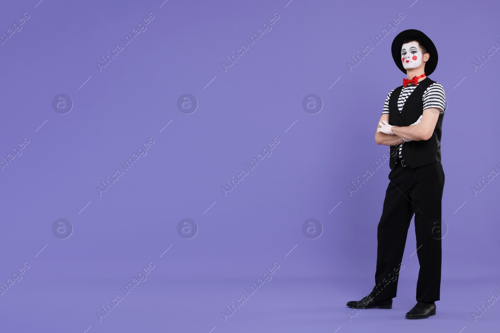 Photo of Funny mime artist in hat posing on purple background. Space for text