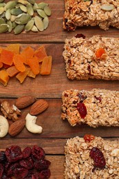 Photo of Different tasty granola bars and ingredients on wooden table, flat lay